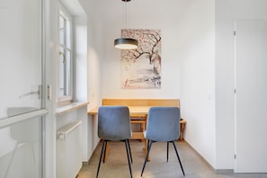 Ein Essbereich mit Tisch und zwei Stühlen, einer Pendelleuchte und einem Wandbild.