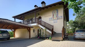 A two-story building with a balcony, a staircase, and a mural on the wall.