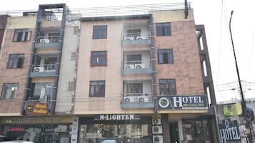 Un edificio de varios pisos con un hotel llamado 'Hotel Me-Casa Inn' en la planta baja, que presenta un letrero con información de contacto.
