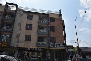 Un hotel de varios pisos con balcones, un letrero visible para 'N-Lighten' y un letrero que dice 'Hotel Me-Casa Inn'.