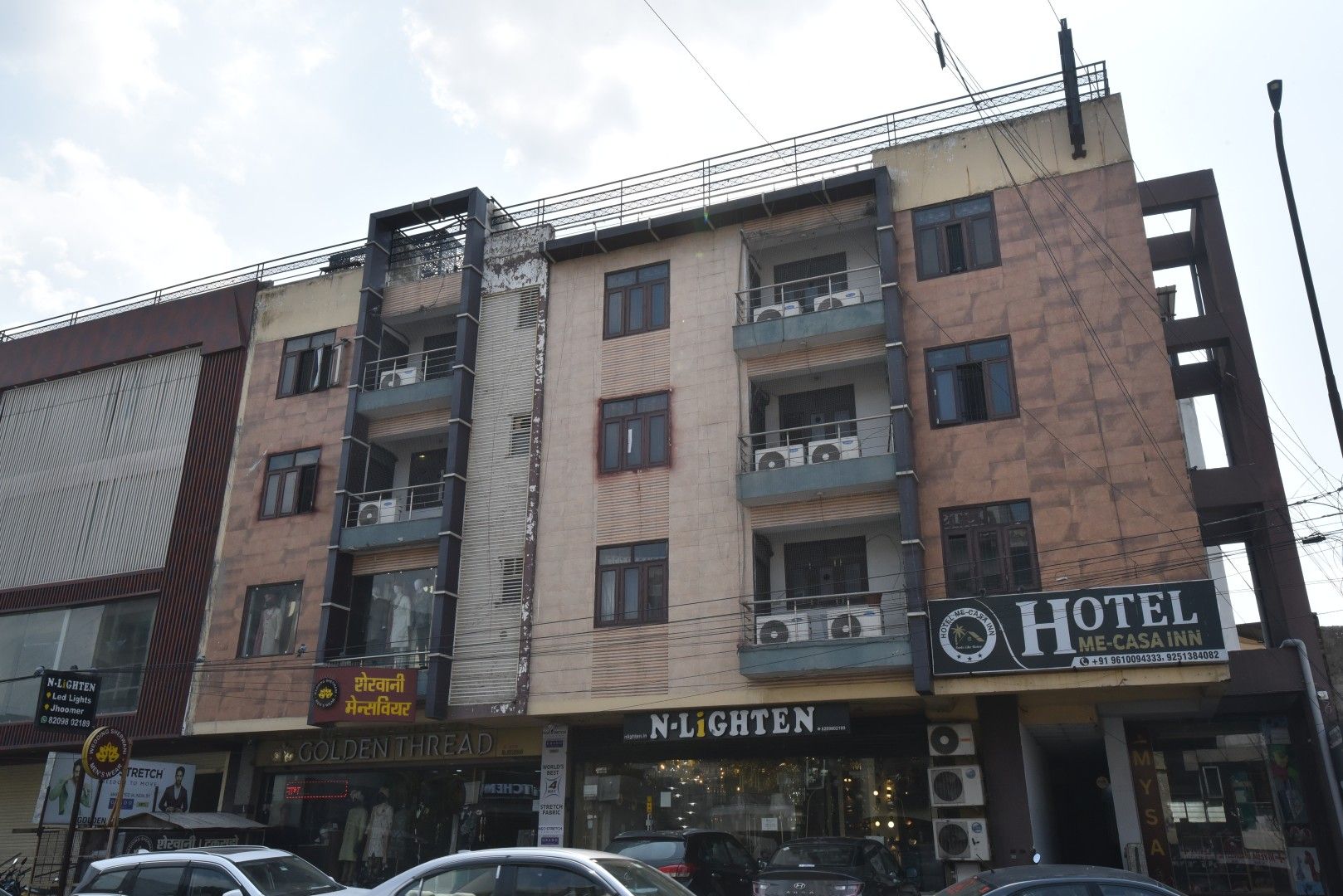 A multi-story building with balconies, a hotel sign, and a storefront with a sign that reads 'N-LIGHTEN'.