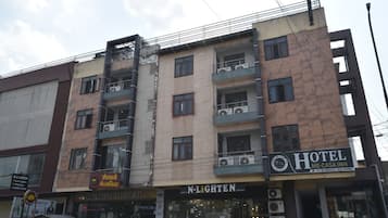 A multi-story building with balconies, a hotel sign, and a storefront with a sign that reads 'N-LIGHTEN'.