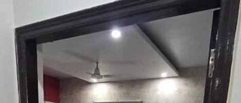 Quarto com cama, ventilador de teto e luminária.