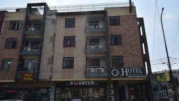 Un edificio de varios pisos con un hotel llamado 'Hotel Me-Casa Inn' en la planta baja, con balcones y unidades de aire acondicionado.