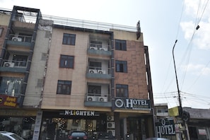 Un hotel de varios pisos con balcones, un letrero visible que dice 'N-Lighten' y un letrero que indica 'Hotel Me-Casa Inn'.