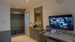 Ein modernes Zimmer mit Fernseher, der einen Streaming-Dienst anzeigt, einer Uhr und einer Pflanze.