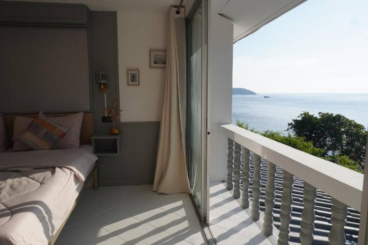 Une chambre à coucher avec un lit, une table de chevet, une lampe et une vue sur la mer.