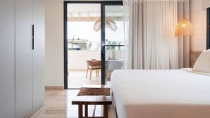 Habitación de hotel con cama, una mesa, una silla, balcón con vistas y una lámpara colgante.
