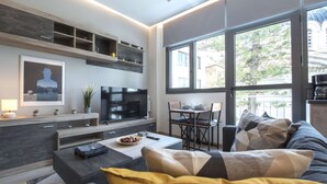 Un salon moderne avec un téléviseur, un canapé et un coin repas.