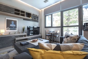 A modern living room with a TV, sofa, and dining area. - Luxury Haven in the most ideal area of Athens 2 (Athina)