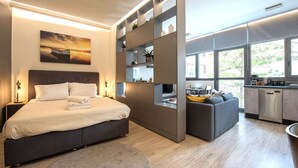 Une chambre moderne comprenant un lit, des tables de chevet, un canapé, un coin repas et une cuisine.