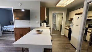 Una cocina moderna con una isla central, armarios de madera y un televisor de pantalla plana montado en la pared.