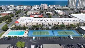 Un hotel con cancha de tenis, piscina y estacionamiento.