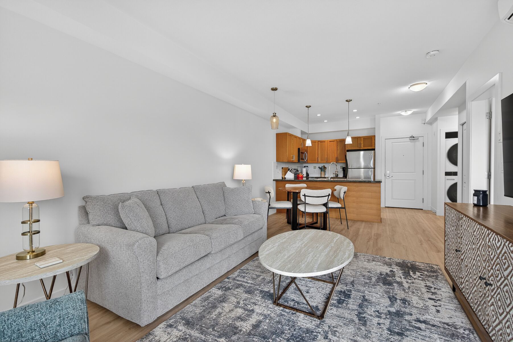 A modern living room with a grey sofa, a round coffee table, and a patterned rug.
