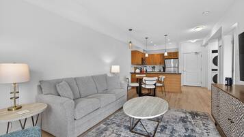 A modern living room with a grey sofa, a round coffee table, and a patterned rug.