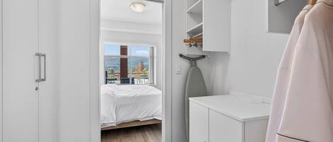 A bedroom with a bed, a wardrobe, a mirror, and a view of the outdoors.