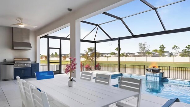 A covered outdoor area with a pool, white table, chairs, and a grill. - Six months to 1 year Home in NONA on the Water, Gated Community, in Orlando, FL! (Orlando)
