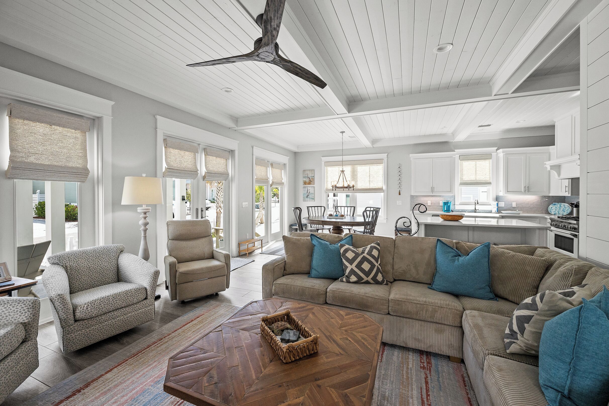 A spacious living room with a large sofa, a coffee table, and a ceiling fan.