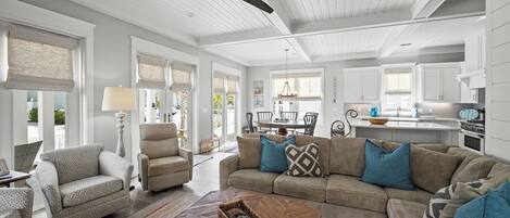 A spacious living room with a large sofa, a coffee table, and a ceiling fan.