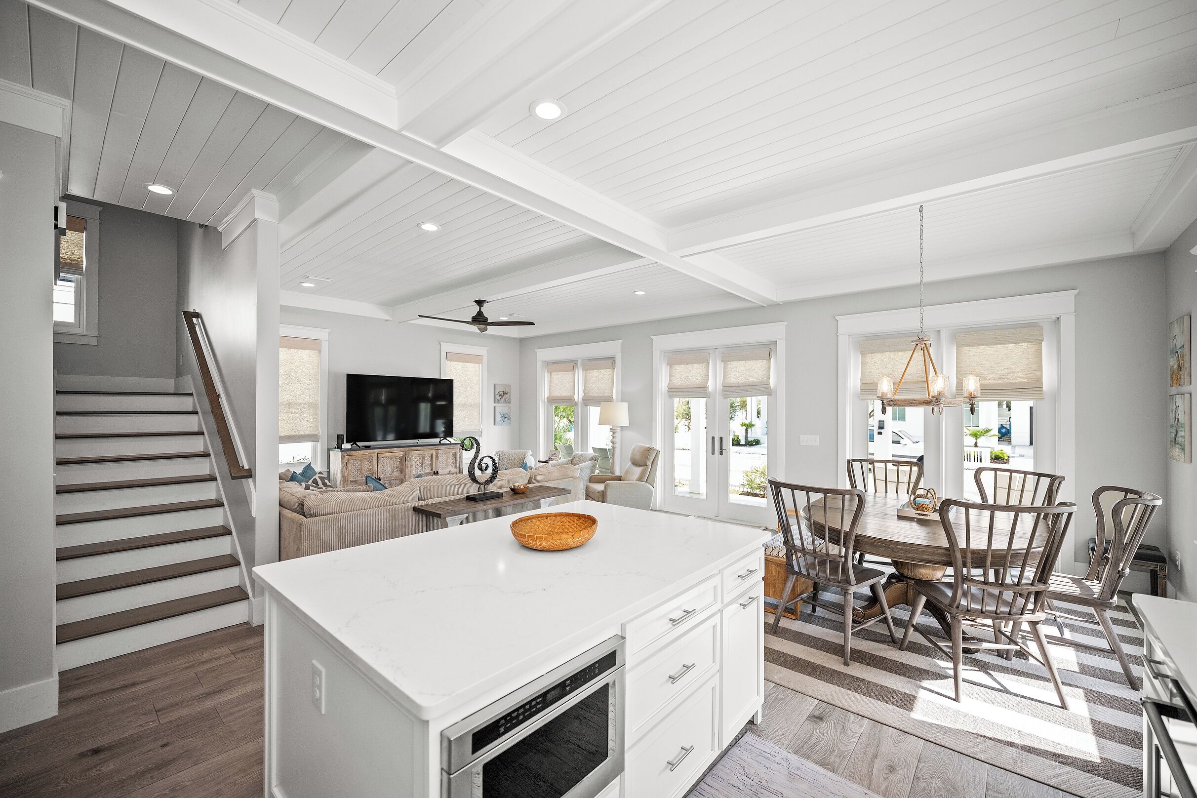 A spacious kitchen with a large island, wooden dining table, and chairs.