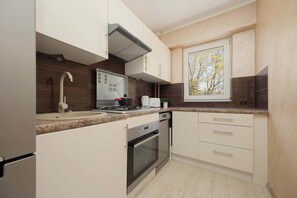 Una cocina moderna con horno empotrado, lavavajillas y ventana con vistas a árboles.
