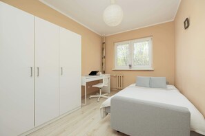 Un dormitorio con cama, escritorio y armario.