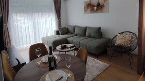 Una sala de estar moderna con comedor, un conjunto de sofás, una silla y un cuadro en la pared.