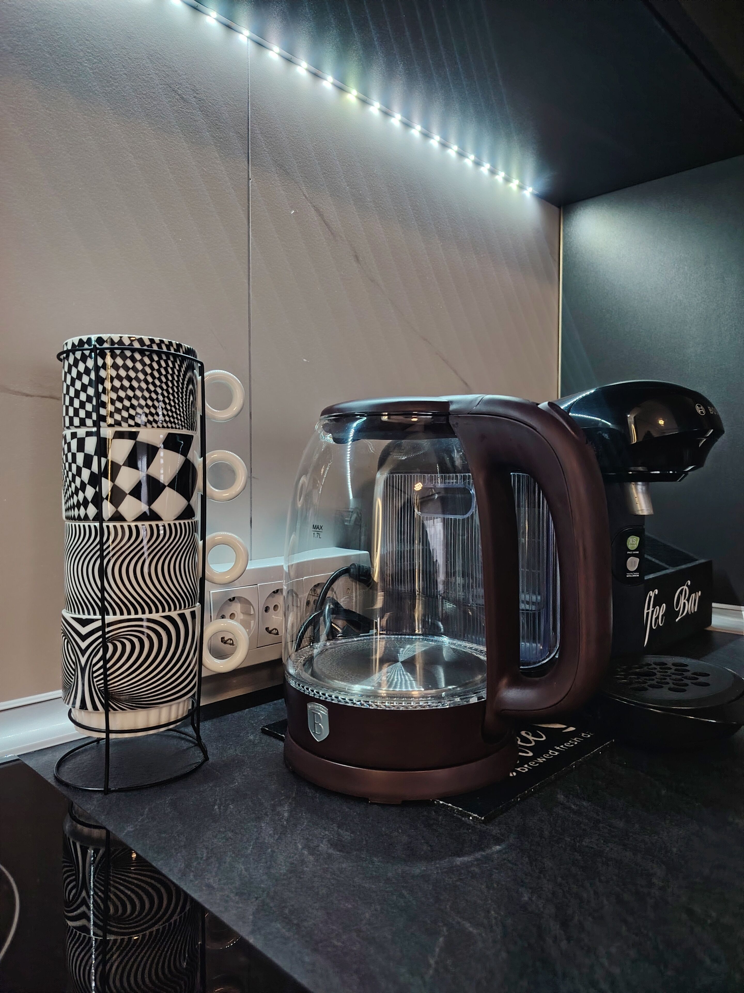 A kitchen counter with a coffee maker, a patterned mug holder, and a coffee grinder.