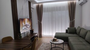 Una sala de estar moderna con sofá, mesa de comedor, sillas, mesa de centro y televisor.