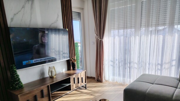 Una sala de estar moderna con un televisor de pantalla plana, un mueble de entretenimiento de madera y una mesa de centro redonda de mármol.