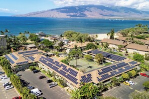 A residential area with solar panels on rooftops, a parking lot, and a view of the ocean and mountains. - 2nd floor, updated studio, across from the beach! - Kihei Bay Surf A207 (Kihei)
