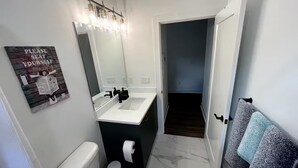 Een badkamer met toilet, wastafel en spiegel.