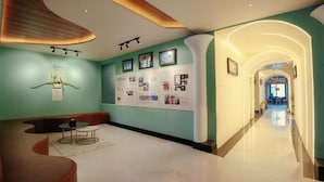 A modern lobby with a curved ceiling, a reception desk, a seating area, and a wall with informational displays.