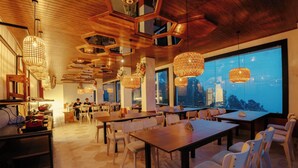 A restaurant with hexagonal ceiling panels, woven pendant lights, and large windows offering a view.