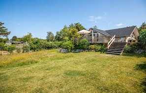 A house with a deck, a staircase, and a grassy yard. - 3 bedroom amazing home in Ebeltoft (Ebeltoft)