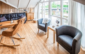 A cozy room with a wooden floor, a black leather sofa, a blue armchair, a wooden rocking chair, and a small table with a globe. - 3 bedroom amazing home in Ebeltoft (Ebeltoft)