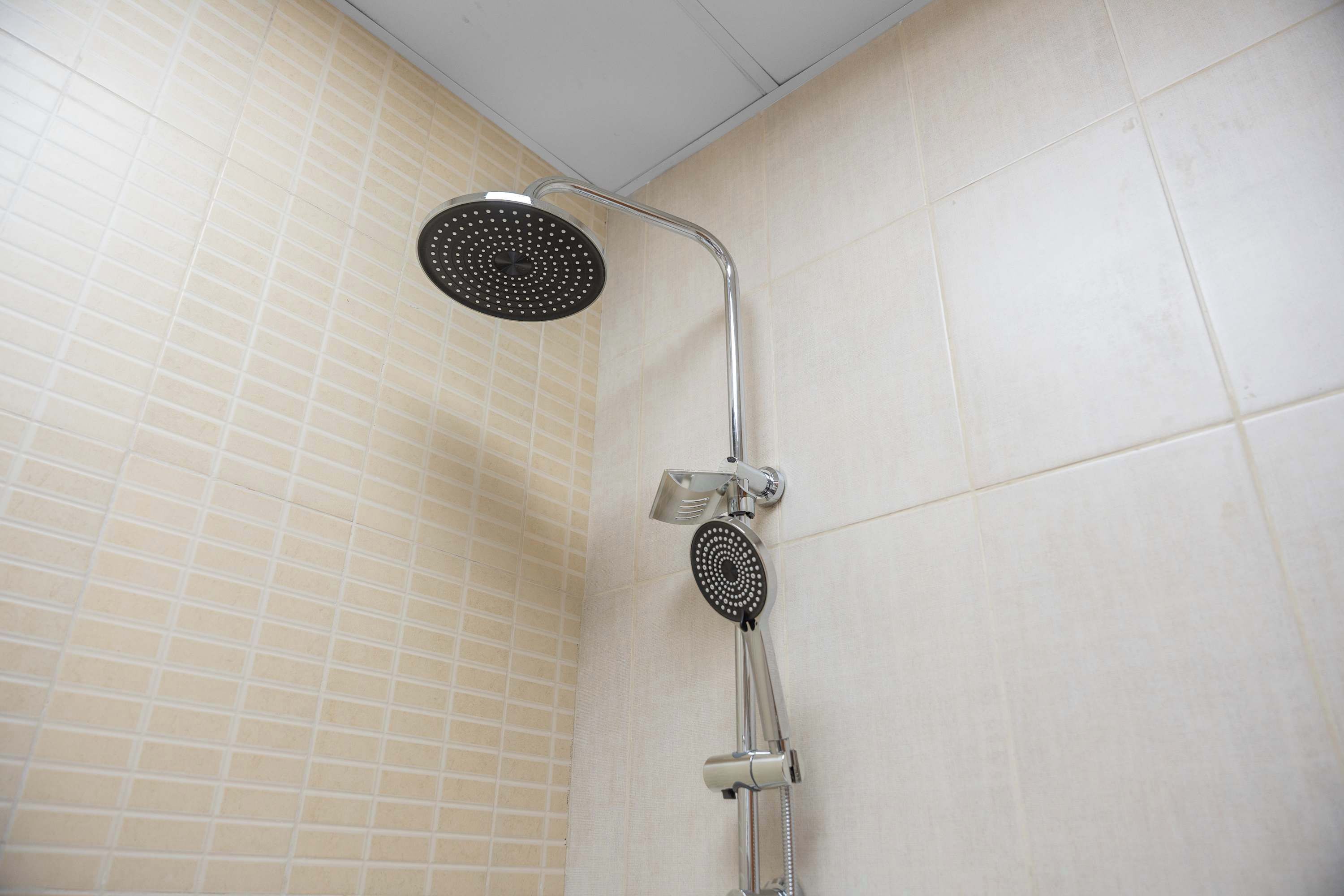 A shower with a handheld showerhead and a wall-mounted control valve.