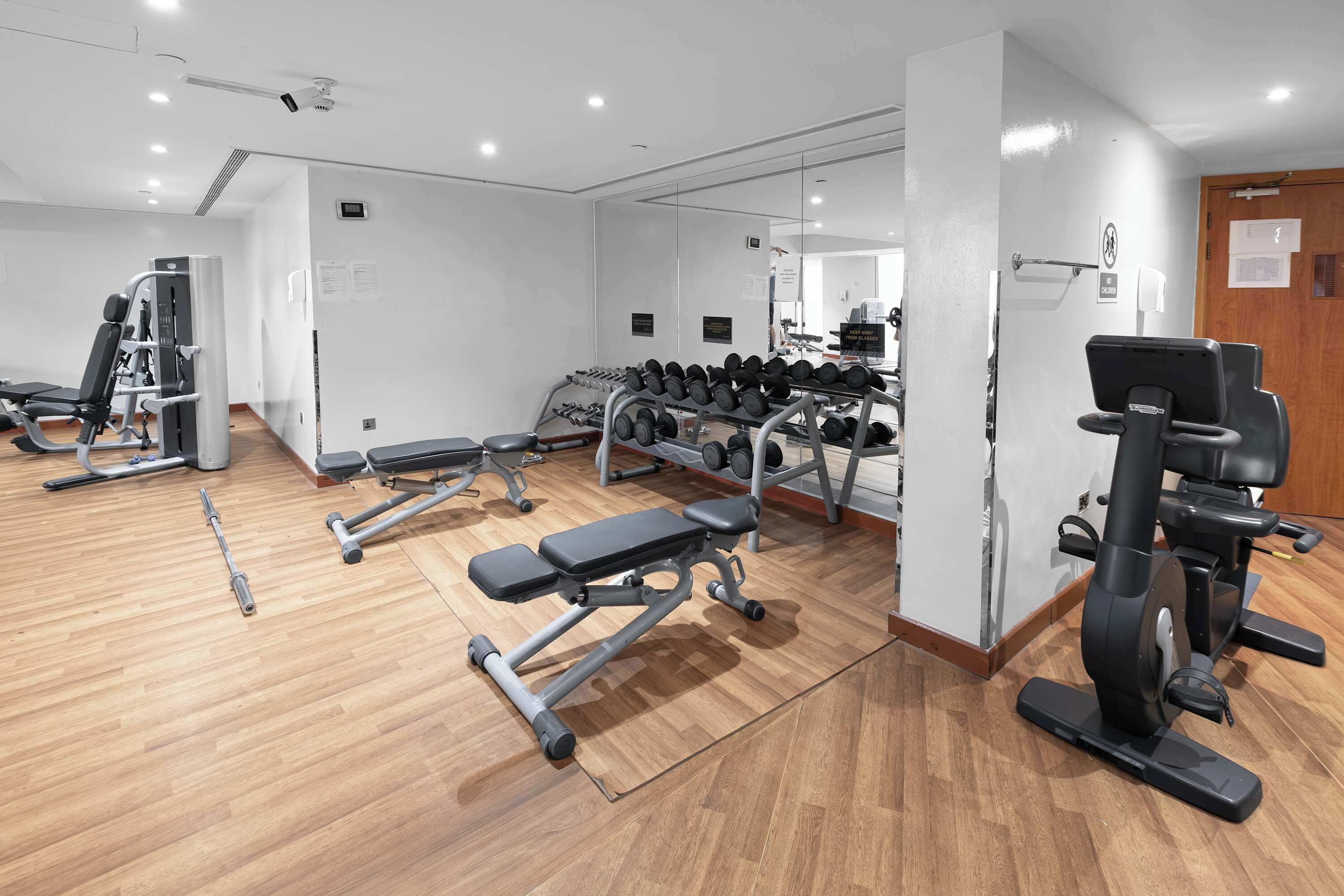 A gym with various exercise equipment, including dumbbells, a bench, and a treadmill.