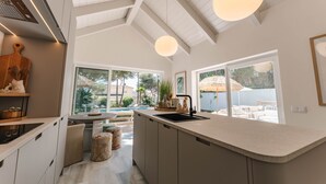 A modern kitchen with a large island, a built-in oven, and a view of the outdoor patio.