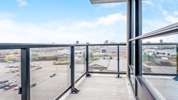 A balcony with a view of a parking lot and buildings. - Modern High Rise Condo w Private Patio Downtown (Kitchener)