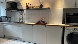A modern kitchen with a microwave, washing machine, and various kitchen utensils. - Place de la Madeleine (Paris)