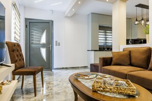 A modern living room with a brown leather sofa, a tufted armchair, and a coffee table with a tray. - Hidden Gem Skopelos - Elegant Island Retreat (Skopelos)