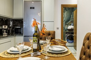 A modern kitchen with a built-in refrigerator, a dining table set with plates, glasses, and a bottle of wine. - Hidden Gem Skopelos - Elegant Island Retreat (Skopelos)