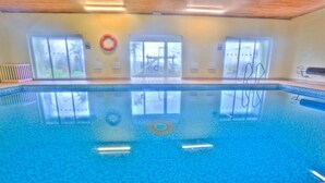 An indoor swimming pool with clear glass walls, a lifebuoy, and a view of a bridge outside. - Poachers Cottage - 3 Bedroom Cottage - Ivy Towers (Tenby)