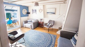 A living room with a sofa, armchair, and a patterned rug. - Old Tom Cottage - 3 Bedroom House - St Florence (Tenby)