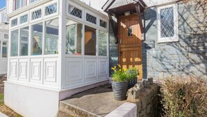A traditional cottage with a conservatory, stone walls, and a wooden door. - Old Tom Cottage - 3 Bedroom House - St Florence (Tenby)