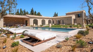 Uma área ao lado da piscina com espreguiçadeiras e uma churrasqueira.