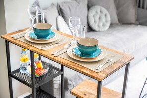 A dining table set with blue bowls and plates, a bottle, and glasses on a shelf. - Free Housekeeping Visits During Your Stay - Stayshort - 1 Bed in Business Bay With Modern Amenities That Sleeps 4 (Dubai)