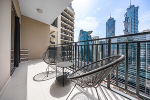 A balcony with two wicker chairs and a small table, overlooking a cityscape with modern buildings. - Free Housekeeping Visits During Your Stay - Stayshort - 1 Bed in Business Bay With Modern Amenities That Sleeps 4 (Dubai)