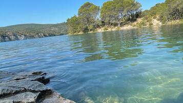 Un lac aux eaux claires, avec des rochers visibles et des arbres en arrière-plan.